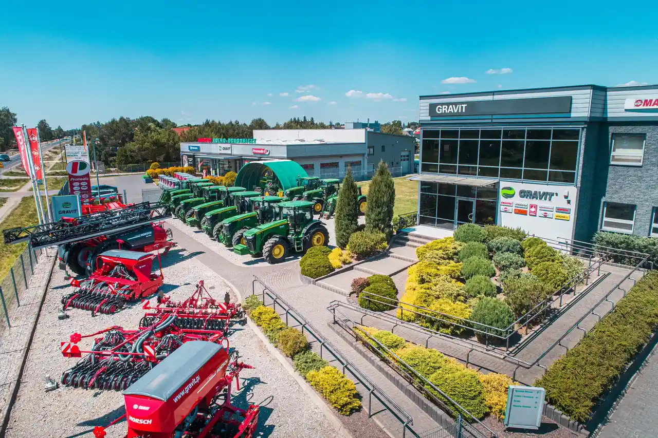 Ciągniki John Deere i maszyny rolnicze stoją przed siedzibą GRAVIT.